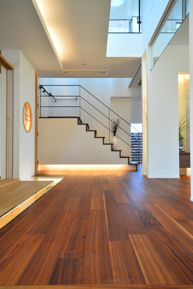 Design ideas for a world-inspired hallway in Other with white walls, brown floors and plywood flooring.
