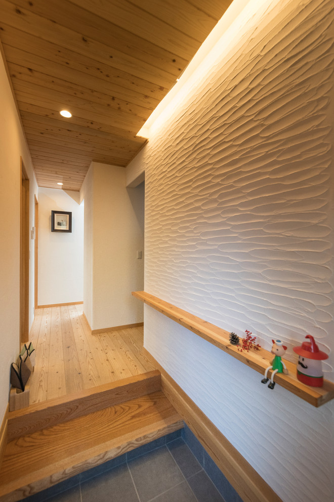Ejemplo de hall asiático con paredes blancas, suelo de madera clara, puerta corredera, puerta de madera clara y suelo beige