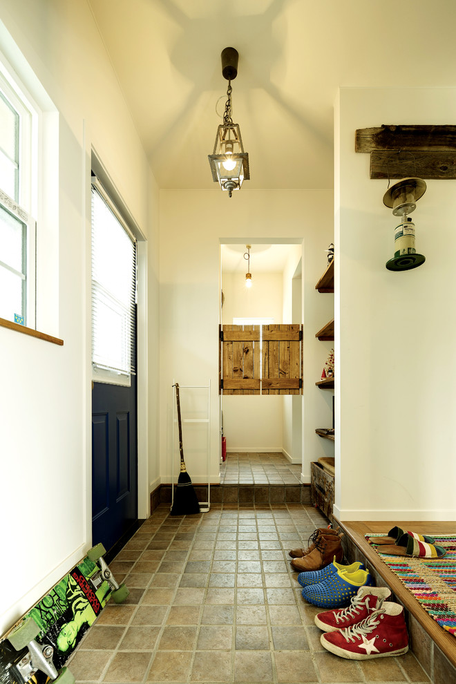 Ispirazione per un corridoio stile marinaro di medie dimensioni con pareti bianche, pavimento in terracotta, una porta singola, una porta blu e pavimento beige