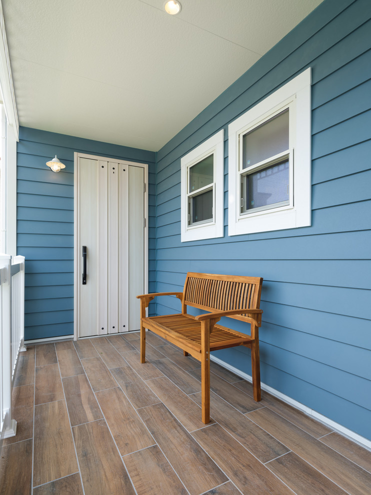 他の地域にあるビーチスタイルのおしゃれな玄関 (青い壁、磁器タイルの床、白いドア、茶色い床) の写真