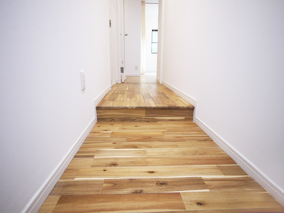 Immagine di un corridoio minimalista con pareti bianche e pavimento in legno massello medio