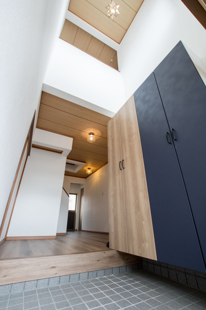 Aménagement d'une entrée asiatique de taille moyenne avec un couloir, un mur blanc, une porte coulissante, une porte en bois brun, du papier peint, un sol en carrelage de porcelaine, un sol gris et un plafond en bois.