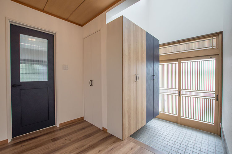 Cette image montre une entrée bohème avec un couloir, un mur blanc, un sol en bois brun, une porte coulissante, une porte en bois brun, un sol marron, un plafond en bois et du papier peint.
