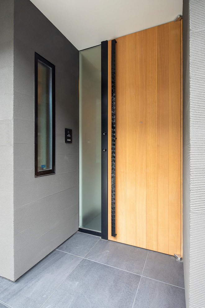 Idee per una piccola porta d'ingresso minimalista con pareti nere, pavimento in gres porcellanato, una porta singola, una porta in legno chiaro e pavimento nero