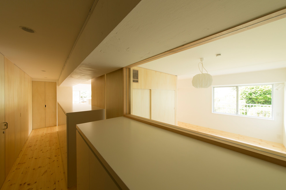 Inspiration pour une entrée minimaliste de taille moyenne avec un couloir, un mur beige, un sol en bois brun, une porte simple, une porte blanche et un sol beige.