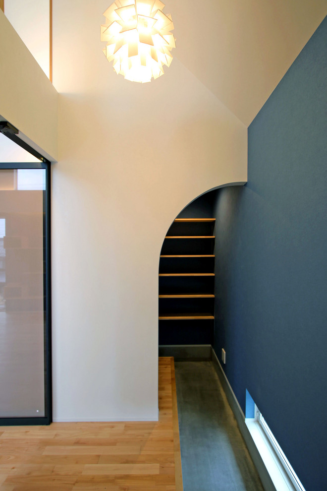 Foto di un corridoio moderno con pareti blu, parquet chiaro, una porta singola, una porta in legno bruno e pavimento beige