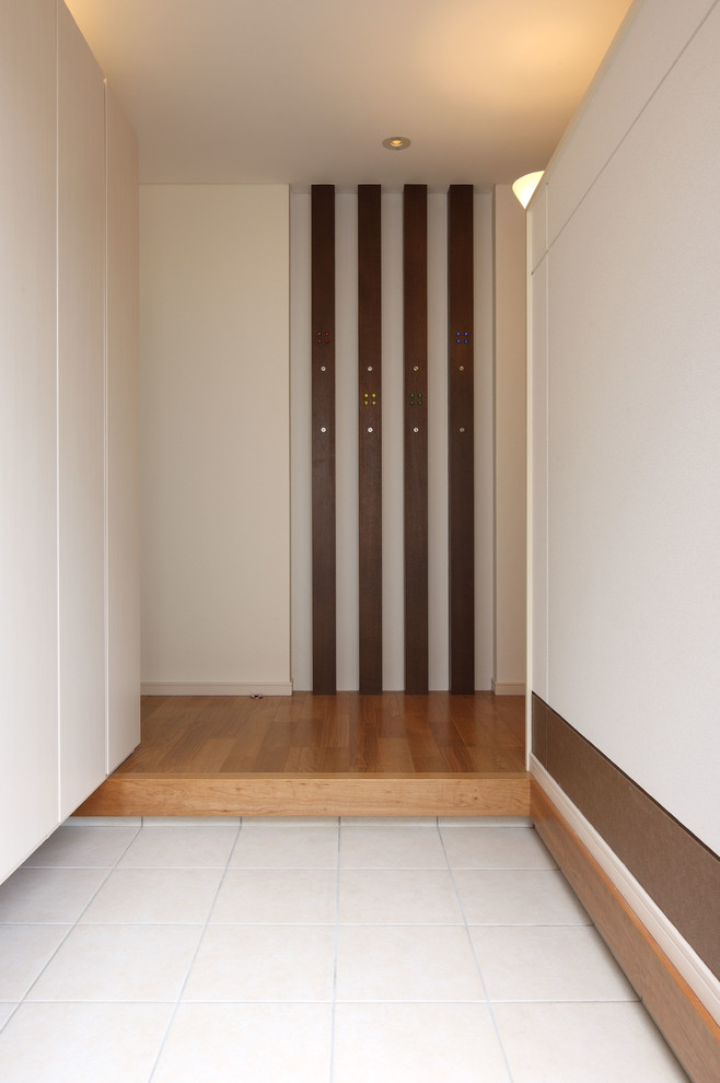 Diseño de hall moderno con paredes blancas, suelo de baldosas de cerámica, puerta simple, puerta marrón y suelo gris