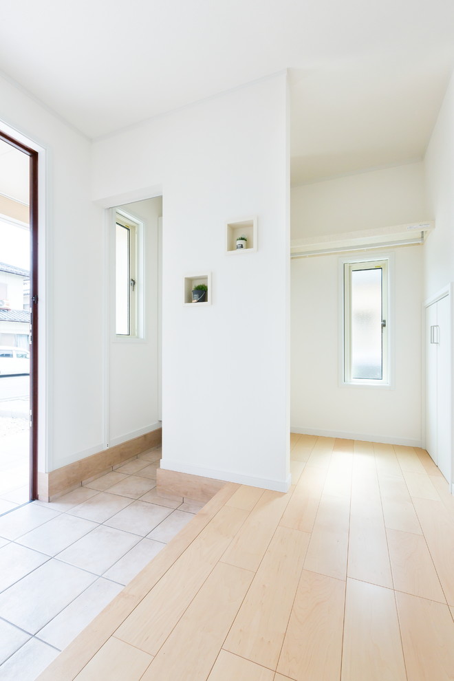 Photo of a modern hallway in Other with white walls, plywood flooring, a single front door, a dark wood front door and beige floors.