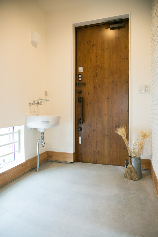 他の地域にある高級な広いコンテンポラリースタイルのおしゃれな玄関 (白い壁、コンクリートの床、木目調のドア、グレーの床) の写真