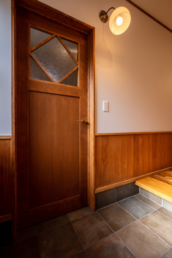 Ejemplo de entrada campestre con paredes blancas, suelo de baldosas de porcelana, puerta simple, puerta de madera oscura, suelo marrón, papel pintado y machihembrado