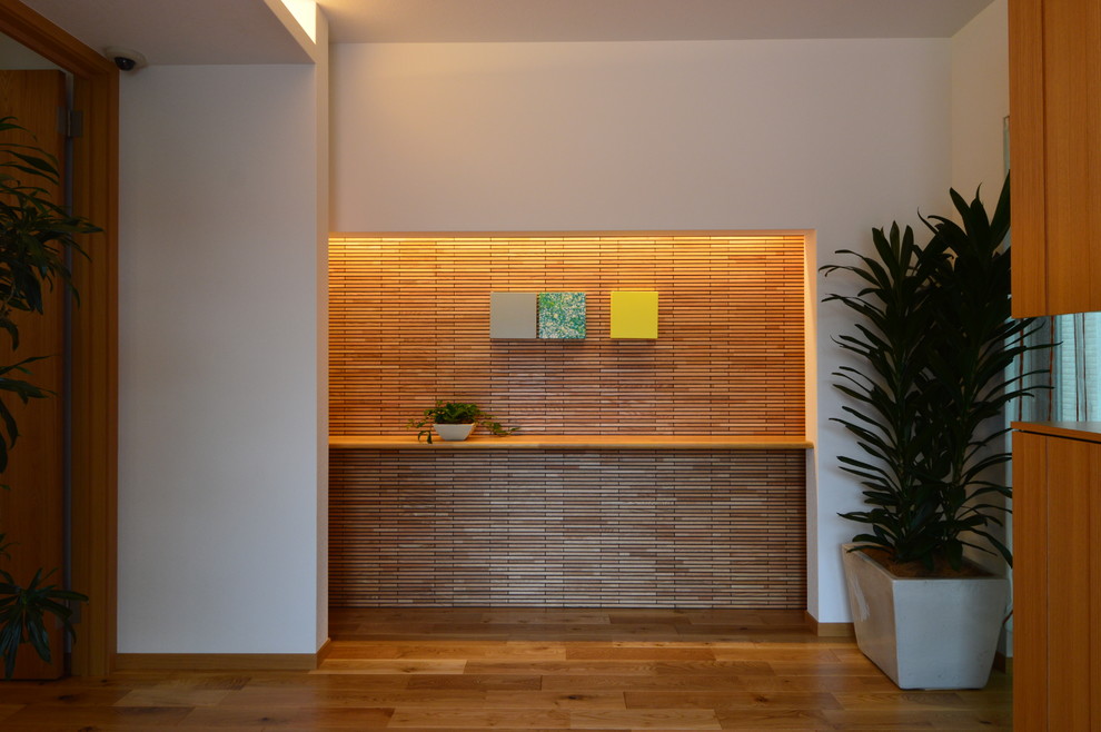 Aménagement d'une grande entrée moderne avec un couloir, un mur marron et un sol en bois brun.