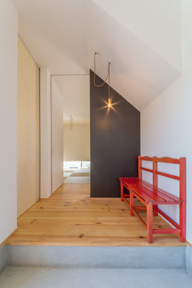 Cette image montre un vestibule design avec un mur blanc et un sol en bois brun.
