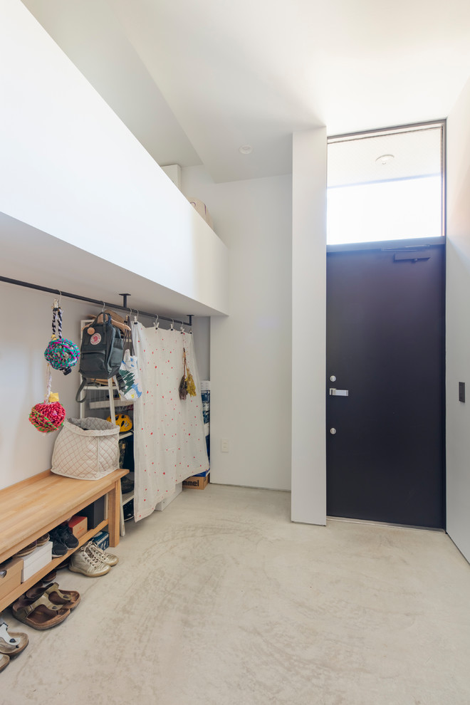 東京23区にあるモダンスタイルのおしゃれなマッドルーム (白い壁、コンクリートの床、黒いドア、グレーの床) の写真