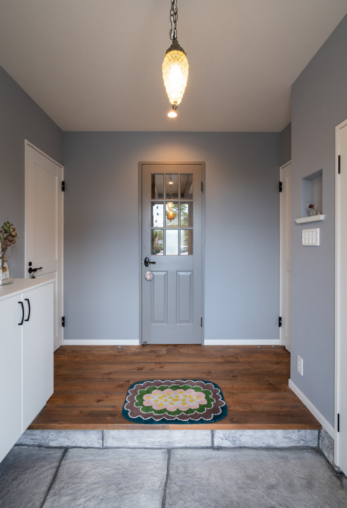 Modelo de entrada romántica con paredes grises, suelo de madera oscura, puerta simple y suelo marrón