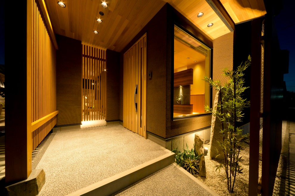 На фото: прихожая в восточном стиле с раздвижной входной дверью, входной дверью из дерева среднего тона и серым полом