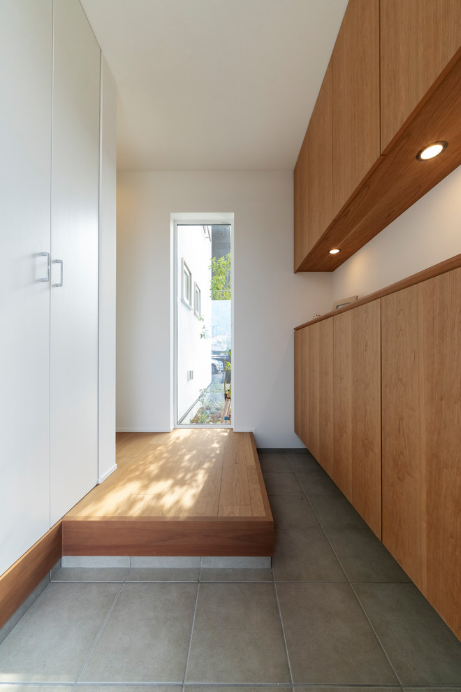 Immagine di un corridoio moderno con pareti bianche, pavimento in legno massello medio, una porta in legno bruno e pavimento marrone