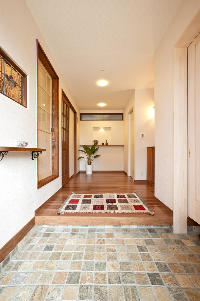 Immagine di un corridoio mediterraneo con pareti bianche, pavimento marrone, pavimento in marmo e una porta marrone