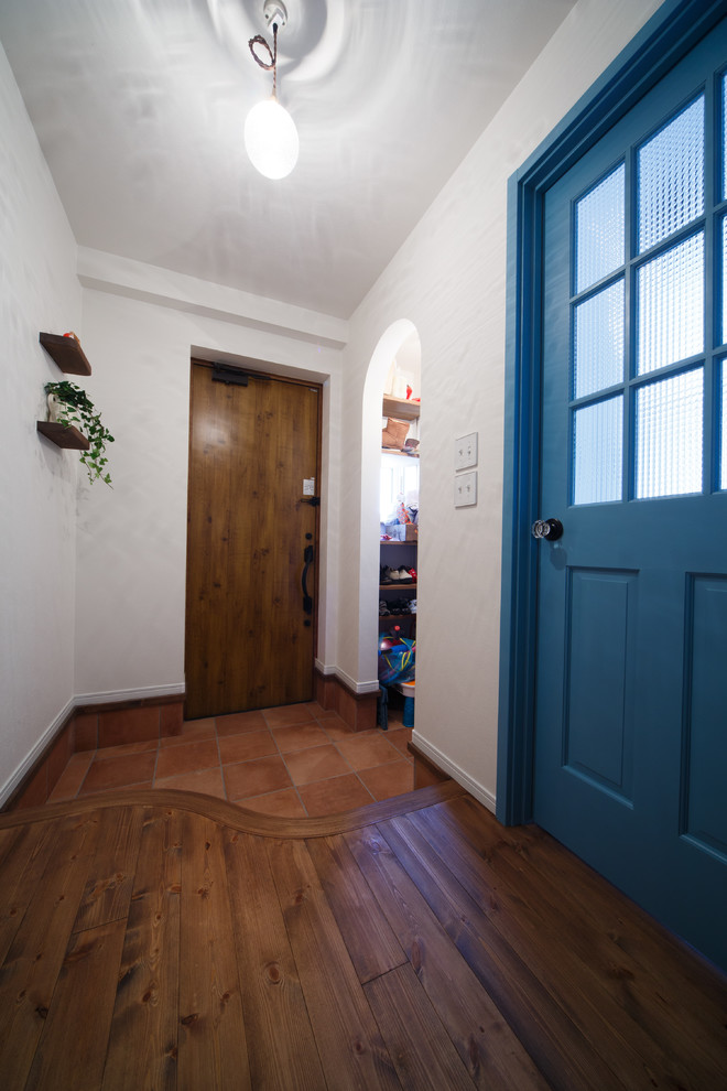 На фото: прихожая в скандинавском стиле с белыми стенами, паркетным полом среднего тона, одностворчатой входной дверью, входной дверью из дерева среднего тона и коричневым полом
