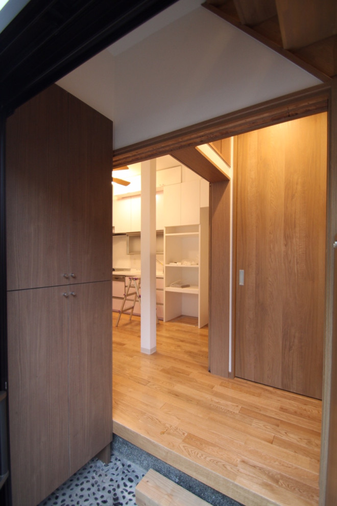 Ejemplo de hall escandinavo pequeño con suelo de terrazo, puerta corredera, puerta marrón, suelo gris, papel pintado y madera