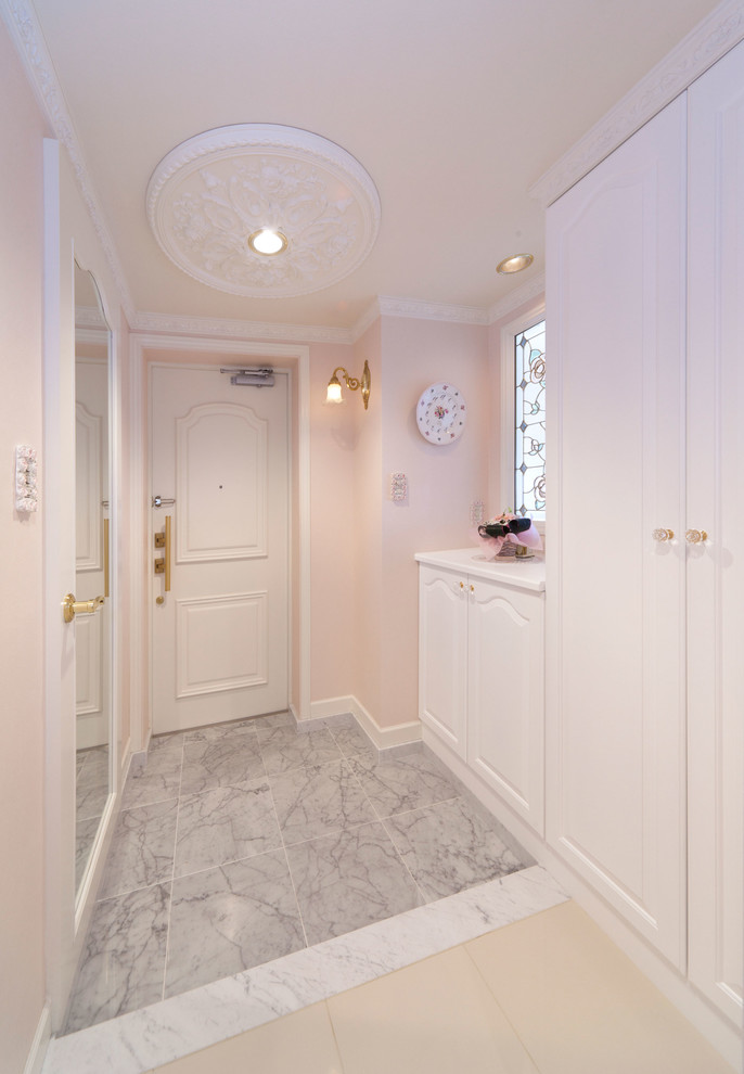 Cette photo montre un vestibule de taille moyenne avec un mur rose, un sol en marbre, une porte simple et une porte blanche.