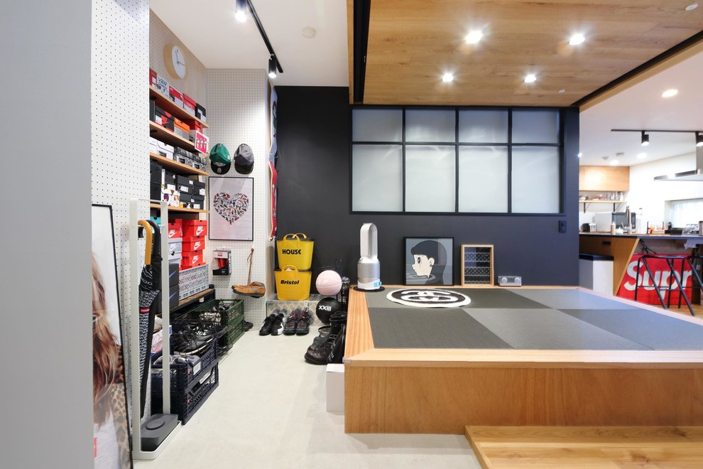 This is an example of an urban boot room in Tokyo with white walls, concrete flooring and grey floors.