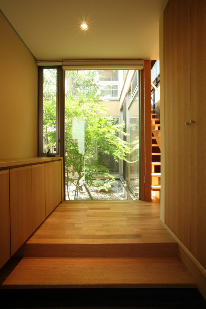 Ejemplo de hall minimalista de tamaño medio con paredes blancas, suelo de madera en tonos medios, puerta simple, puerta de madera oscura y suelo marrón