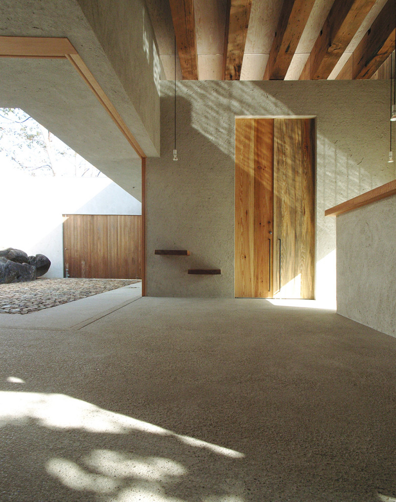Foto di un corridoio minimalista di medie dimensioni con pareti grigie, pavimento in granito, una porta a due ante, una porta in legno chiaro, pavimento grigio e travi a vista