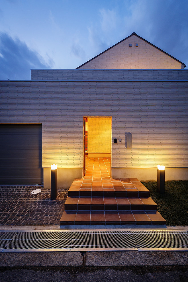 На фото: большая узкая прихожая в современном стиле с коричневым полом, белыми стенами, полом из керамической плитки, одностворчатой входной дверью и коричневой входной дверью с