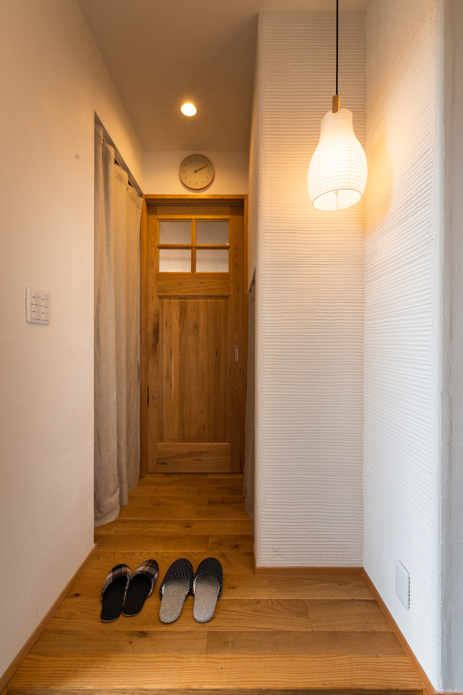 На фото: узкая прихожая в восточном стиле с белыми стенами, паркетным полом среднего тона, одностворчатой входной дверью и разноцветным полом
