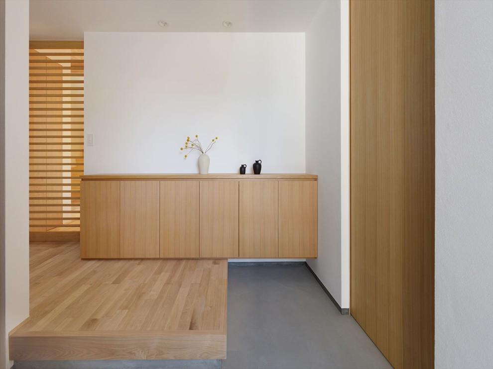 Diseño de entrada de estilo zen con paredes blancas y puerta de madera en tonos medios