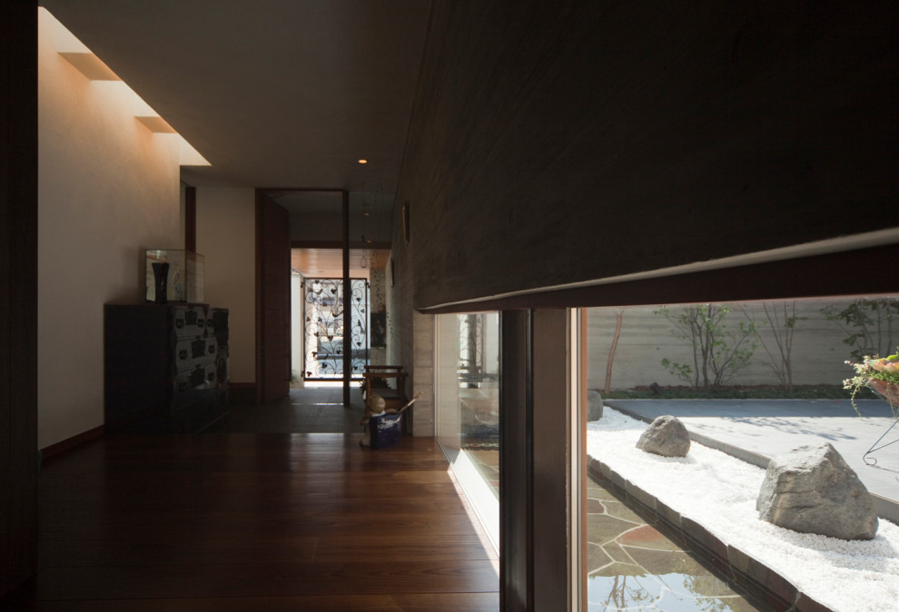 Foto di un grande corridoio minimalista con pareti grigie, pavimento in granito, una porta singola, una porta in legno bruno e pavimento grigio