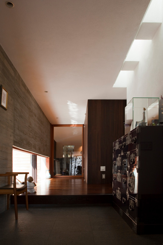 Esempio di un grande corridoio minimalista con pareti grigie, pavimento in granito, una porta singola, una porta in legno bruno e pavimento grigio