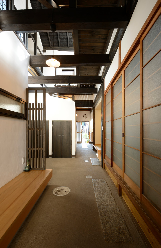 他の地域にある和風のおしゃれな玄関ホール (白い壁、コンクリートの床、黒いドア) の写真