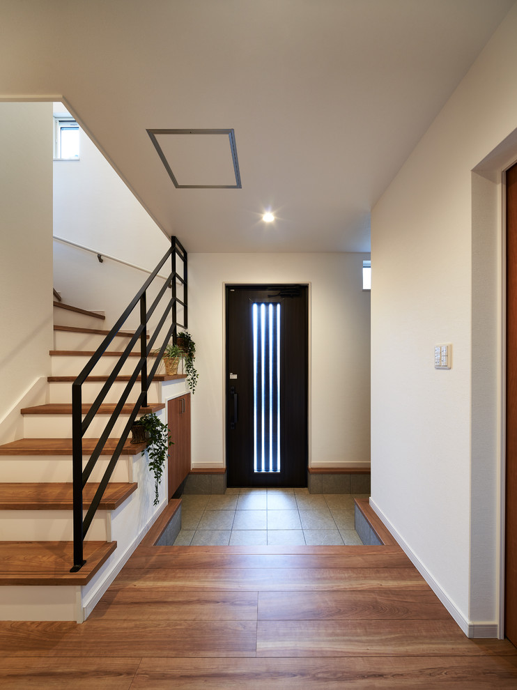 Aménagement d'une entrée moderne avec un couloir, un mur blanc, une porte simple et une porte en bois foncé.