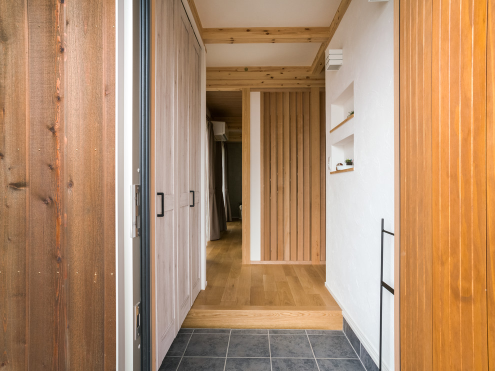 他の地域にある小さなカントリー風のおしゃれな玄関 (白い壁、グレーの床、セラミックタイルの床、木目調のドア) の写真