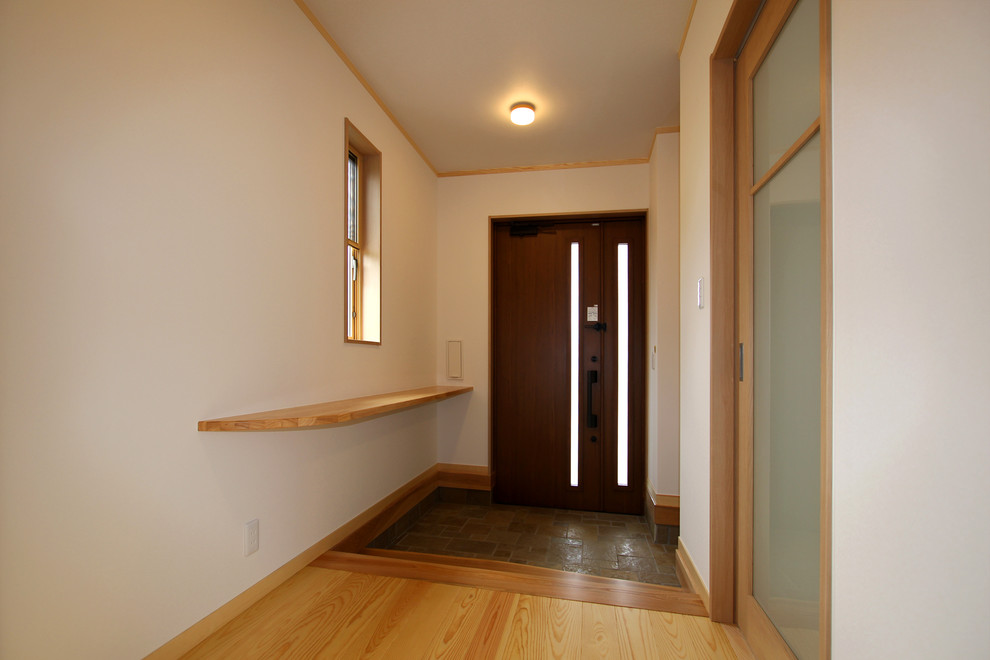 Cette photo montre une entrée asiatique de taille moyenne avec un couloir, un mur blanc, parquet clair, une porte simple, une porte en bois foncé et un sol beige.