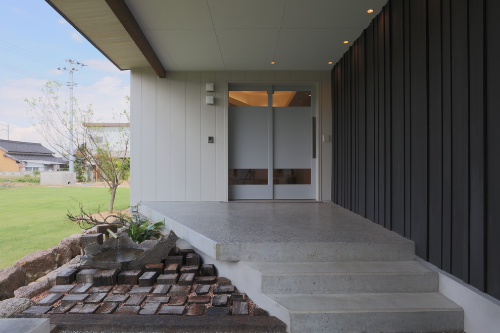 Großer Moderner Eingang mit weißer Wandfarbe, Betonboden, Schiebetür, grauer Haustür und grauem Boden in Sonstige