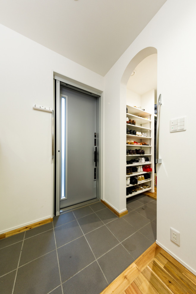 Immagine di un piccolo ingresso con anticamera moderno con pareti bianche, pavimento in gres porcellanato, una porta singola, una porta grigia, pavimento grigio, soffitto in carta da parati e carta da parati