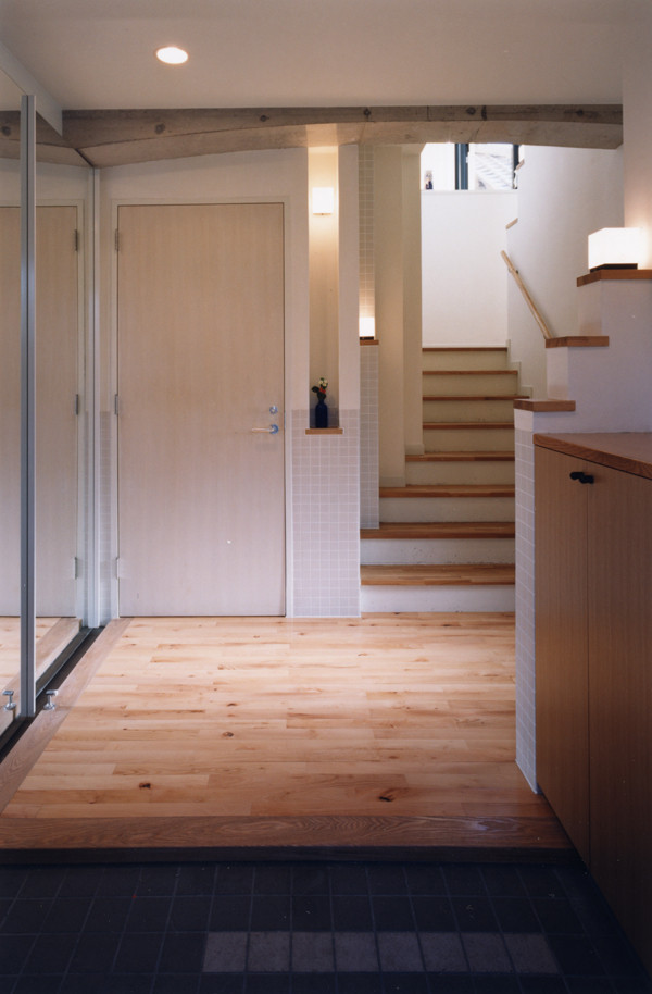 Modelo de hall minimalista grande con paredes blancas, suelo de madera en tonos medios, puerta simple, puerta azul y suelo beige