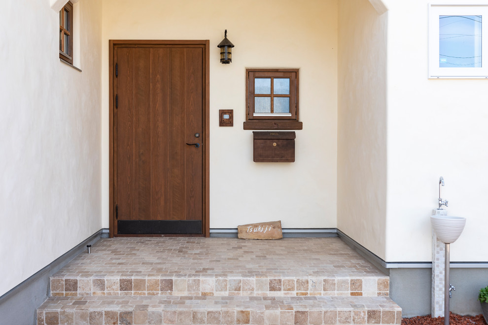 Modelo de hall mediterráneo de tamaño medio con paredes blancas, suelo de travertino, puerta simple, puerta de madera oscura y suelo marrón