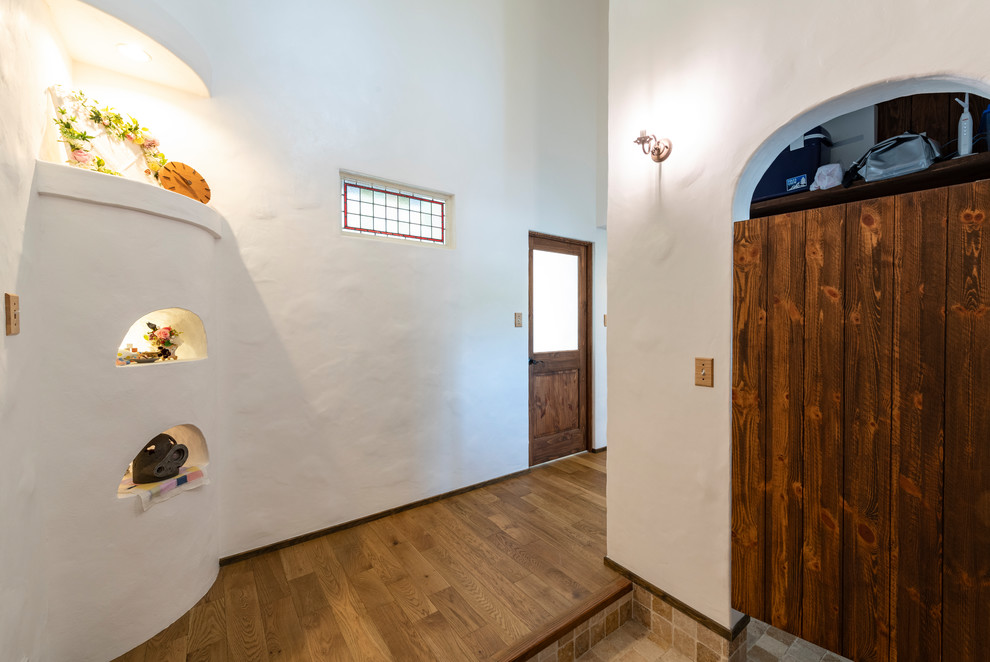 Mittelgroßer Mediterraner Eingang mit Korridor, weißer Wandfarbe, hellem Holzboden, Einzeltür, dunkler Holzhaustür und braunem Boden in Sonstige