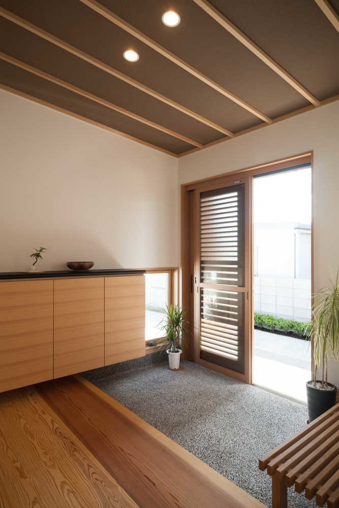 Diseño de entrada asiática con paredes blancas, puerta corredera y suelo marrón