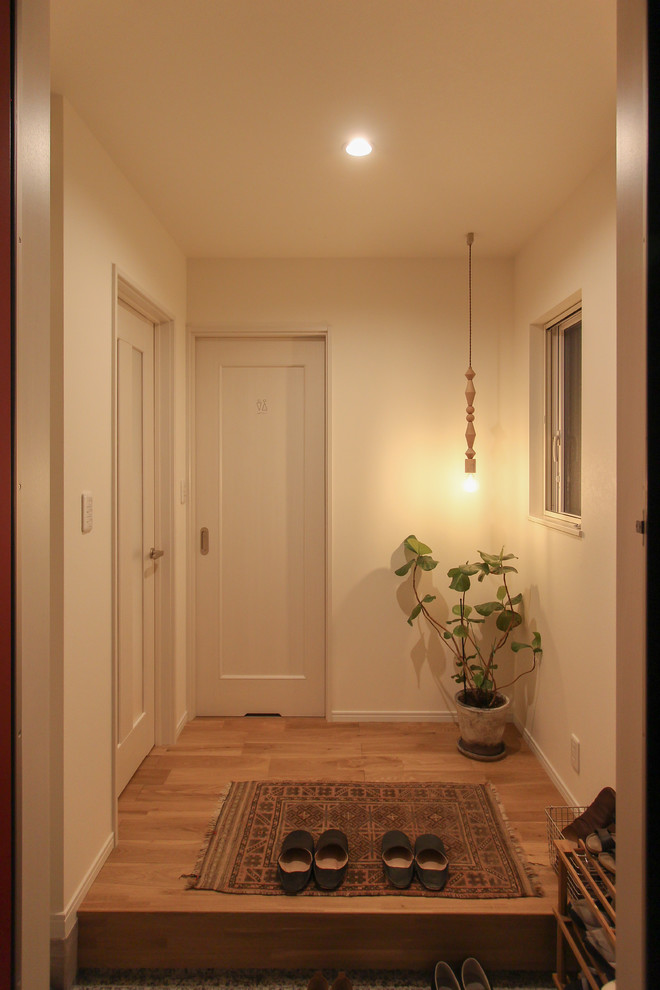 他の地域にあるアジアンスタイルのおしゃれな玄関ホール (白い壁、淡色無垢フローリング、ベージュの床) の写真