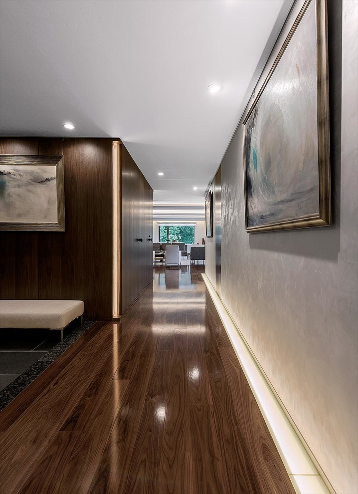 Ispirazione per un corridoio minimalista con pareti bianche, una porta a due ante, una porta in legno scuro e pavimento marrone