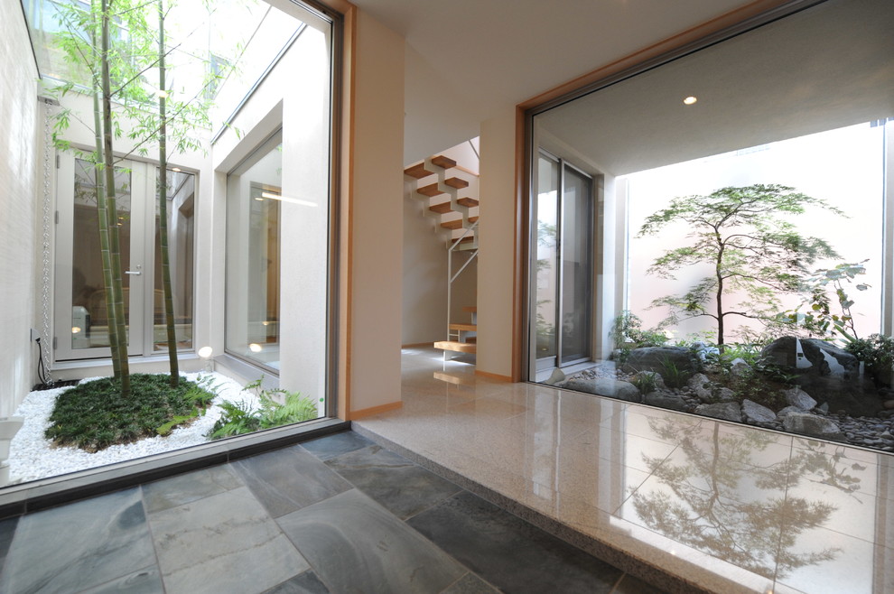 Idée de décoration pour un vestibule asiatique de taille moyenne avec un mur blanc et un sol en ardoise.