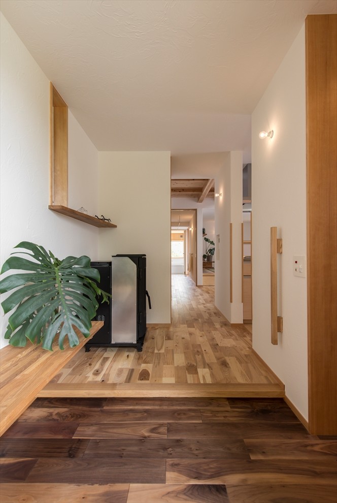 Inspiration for a world-inspired hallway in Yokohama with white walls, medium hardwood flooring and brown floors.