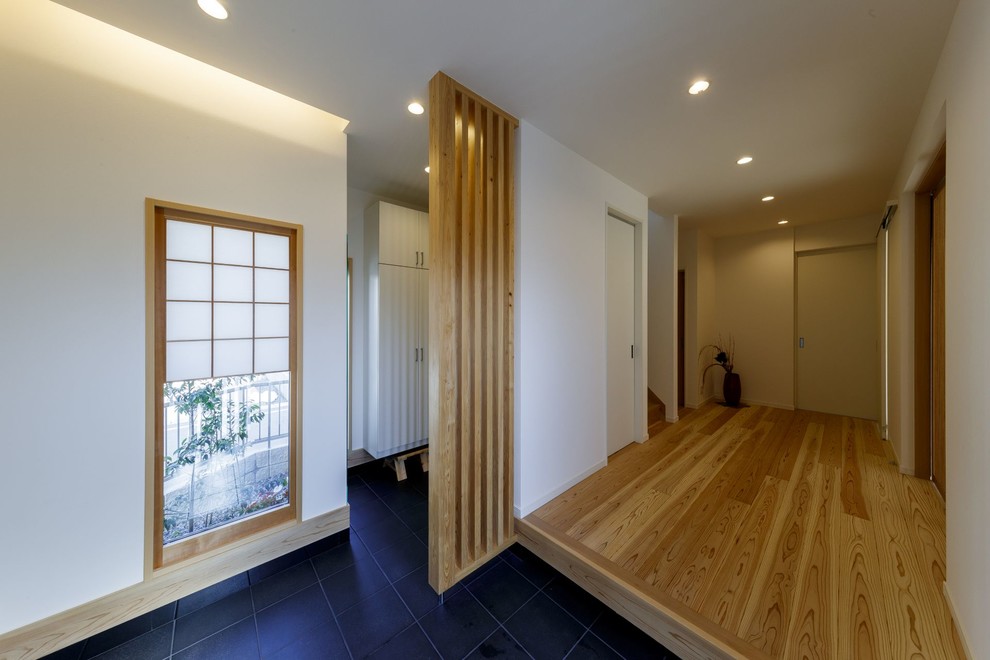Ejemplo de hall de estilo zen de tamaño medio con paredes blancas, puerta corredera, puerta de madera clara y suelo de madera en tonos medios