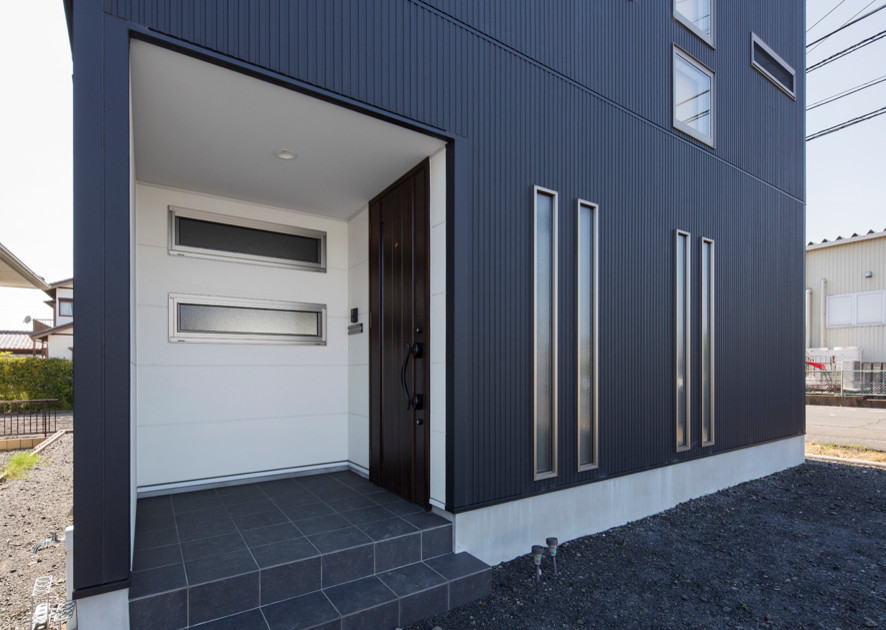 Immagine di una porta d'ingresso moderna di medie dimensioni con pareti nere, pavimento in gres porcellanato, una porta singola, una porta in legno scuro e pavimento nero