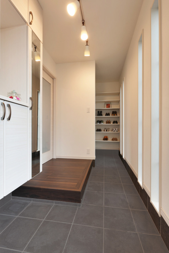 Foto di un corridoio minimalista con pareti bianche, pavimento in compensato e pavimento marrone
