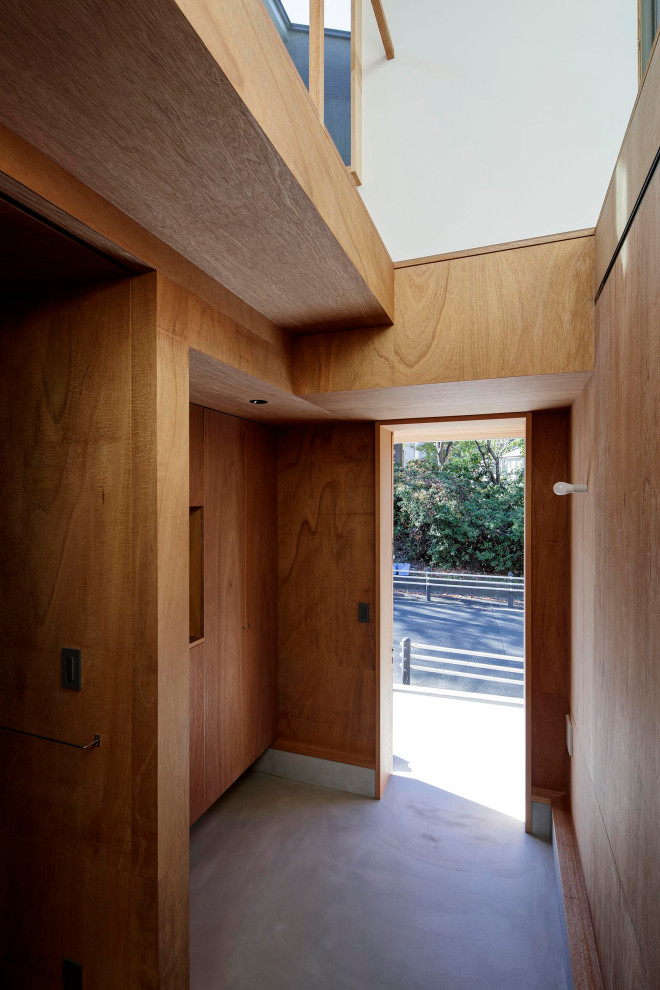 Foto di un piccolo corridoio minimalista con pareti marroni, pavimento in compensato, una porta scorrevole, una porta in legno bruno, pavimento marrone, soffitto in legno e pareti in legno